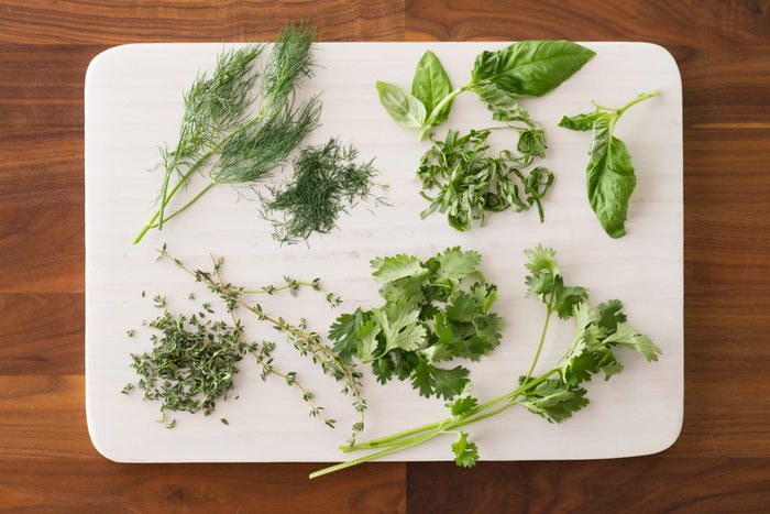 Chopped herbs spread out over a white cutting board