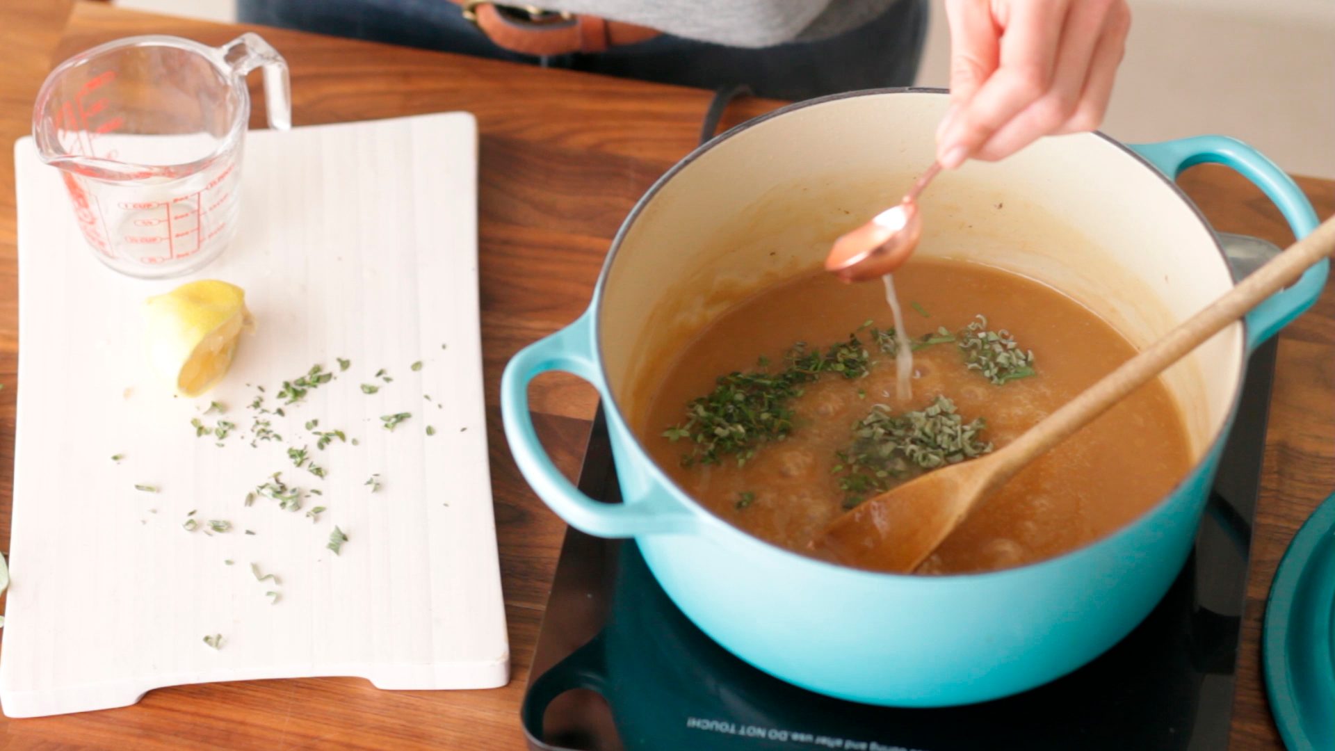 Gravy in a stockpot beside a cutting board and measuring cup