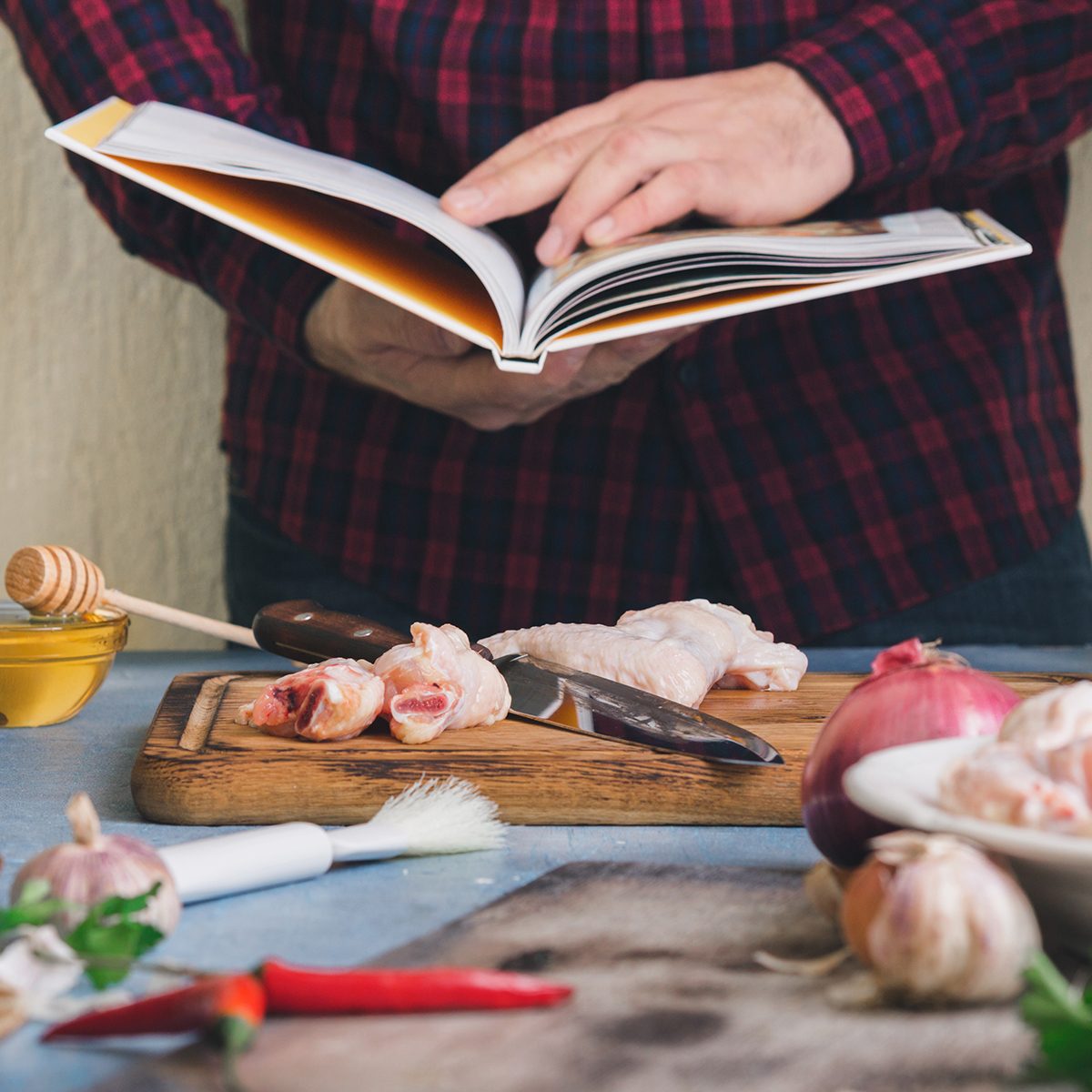 Man prepares chicken wings with cranberry sauce in a home kitchen