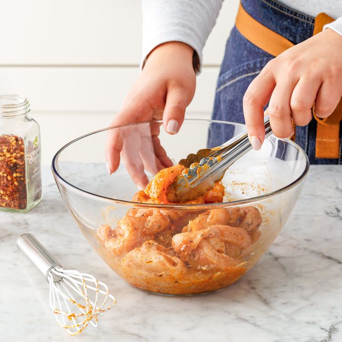 Marinating Chicken in a Large Glass Bowl on Marble Surface