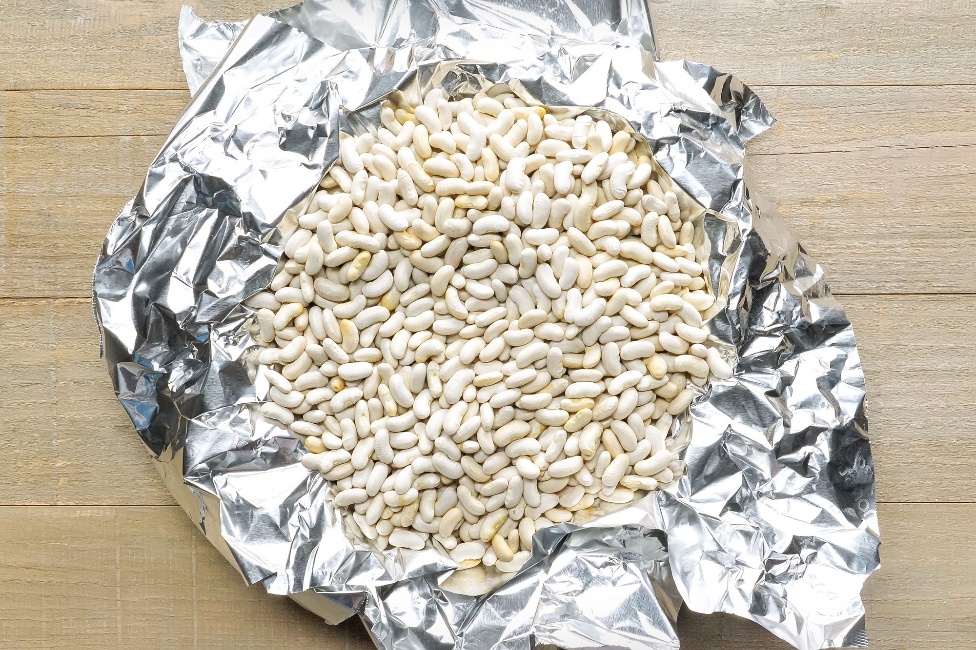 Dried Beans in Silver Foil on Wooden Surface