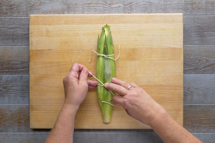 Replacing husks and tie with kitchen string over wooden board