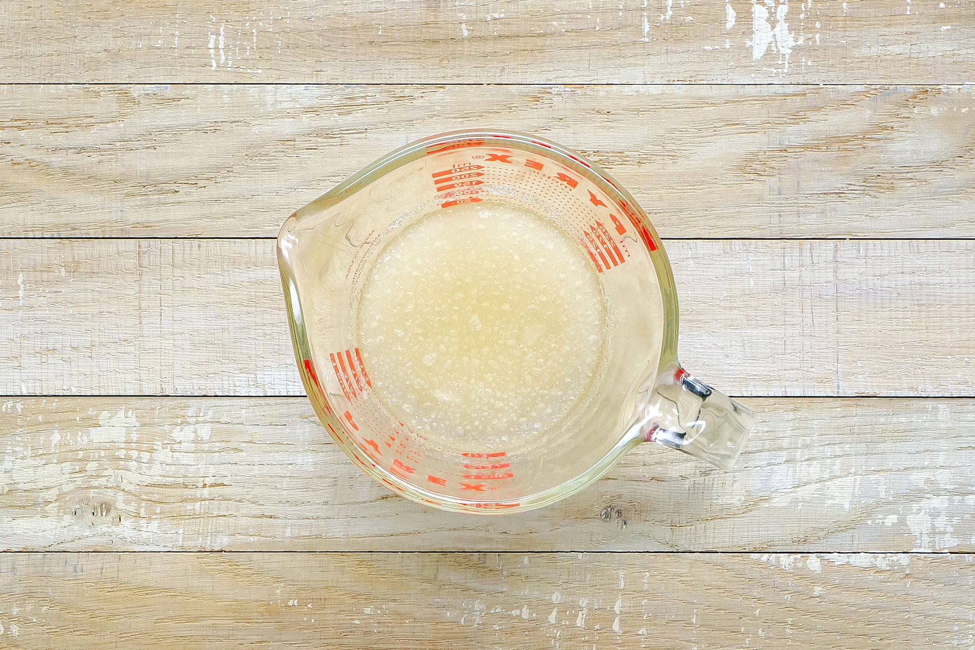 Gelatin and Water in a Measuring Jug on Wooden Surface