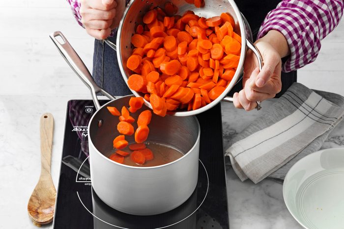 A Person Pouring Carrots Into a Pot