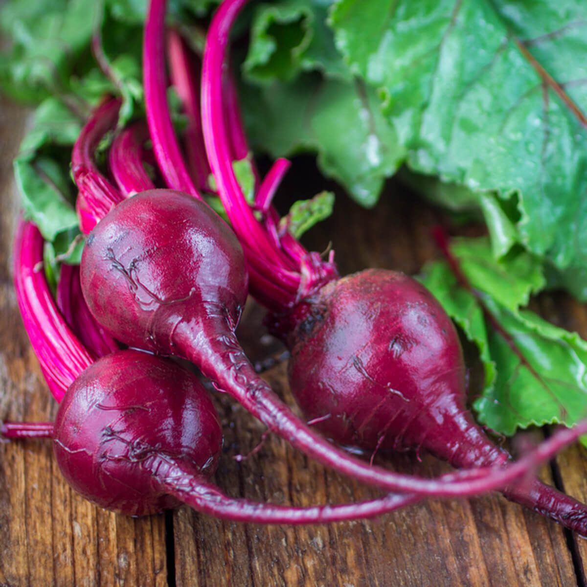 Organic red beets with green leaves on an old wooden table. Rustic style