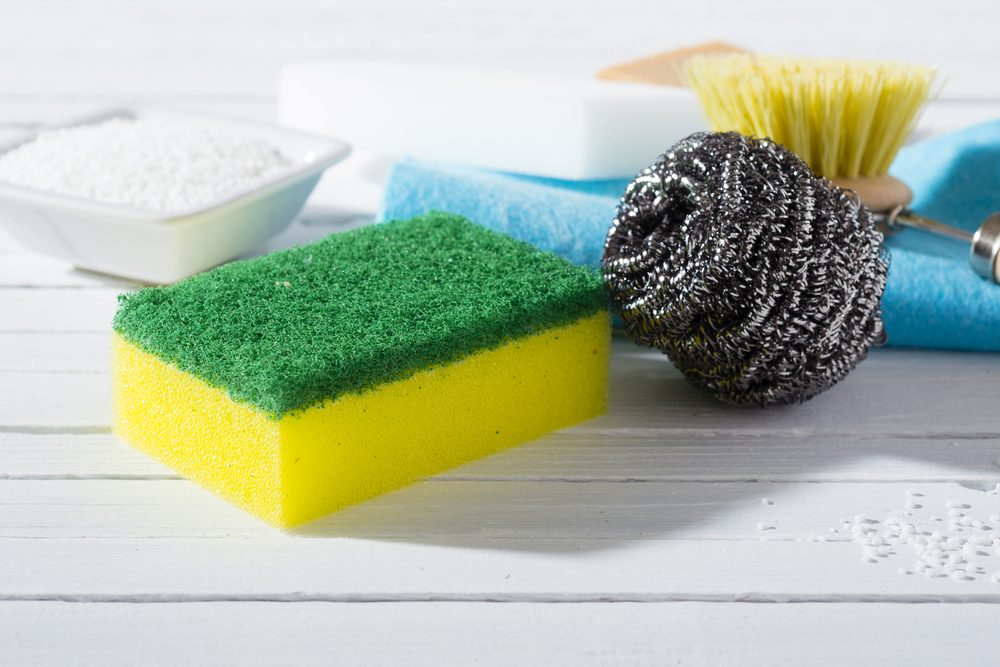 citric acid, cleaning brush, steel wool, sponges and bar of soap on white wooden table background