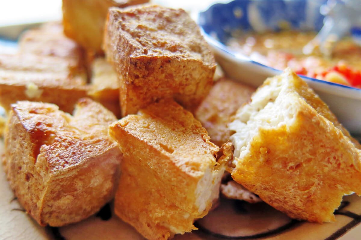 Deep fried Tofu cut in small piece om plate with blurry bowl of peanut sweet chili sauce, Chinese food, home cooking concept