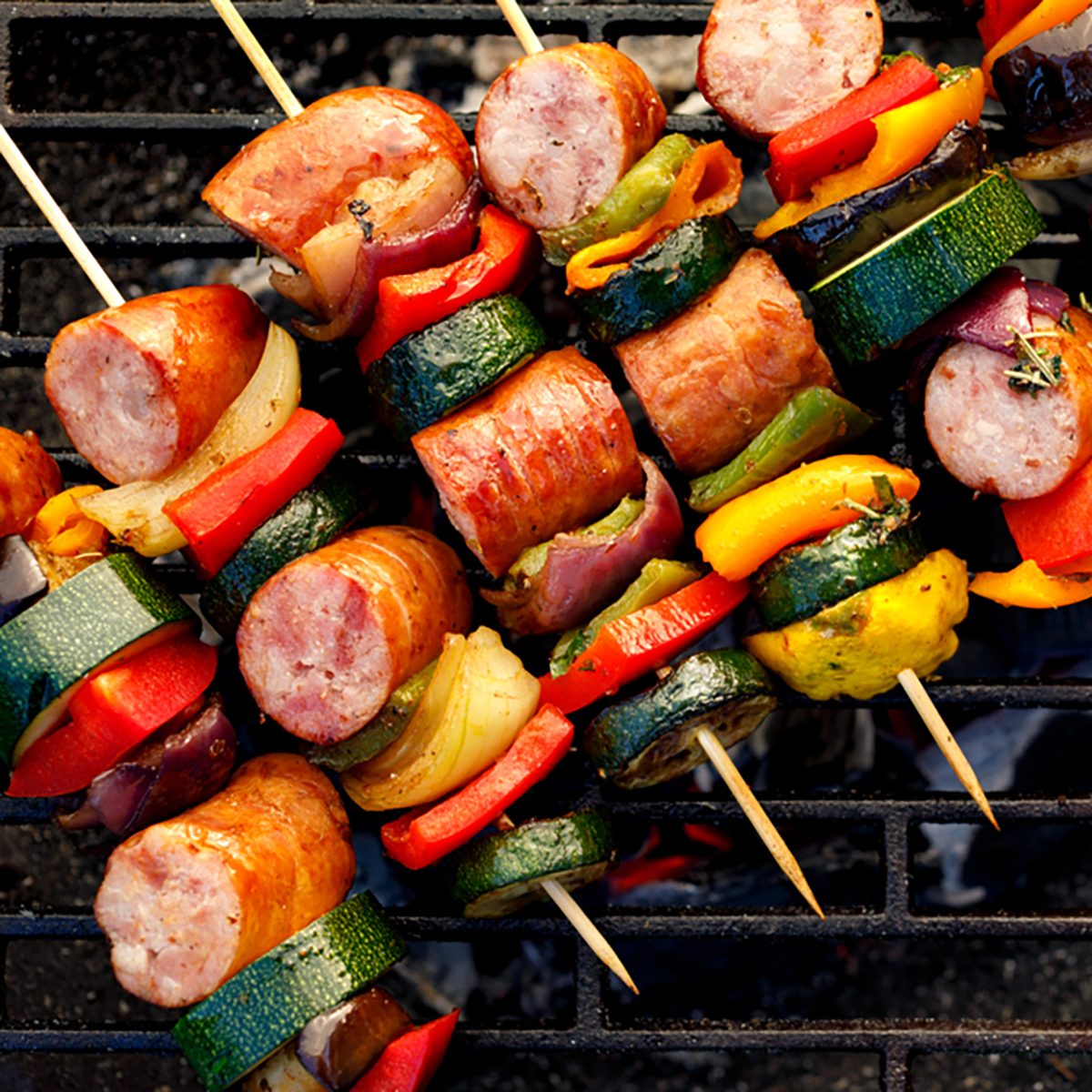 Grilled skewers of meat, sausages and various vegetables on a grill plate, outdoors, top view. Grilled food, bbq