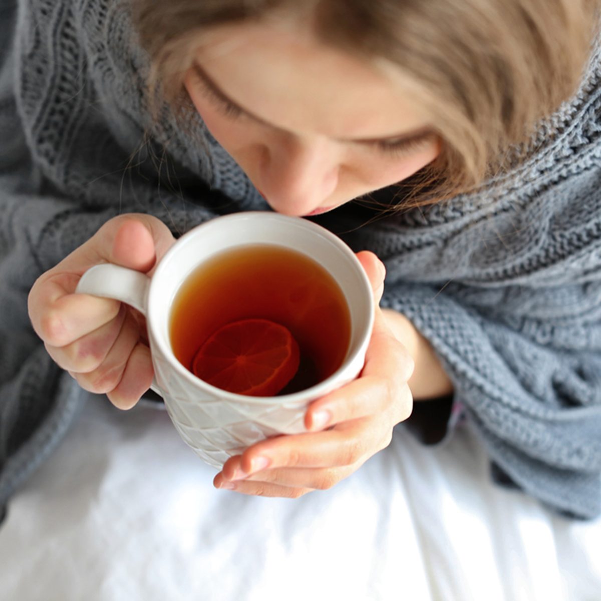 Young ill woman with cup of hot tea at home