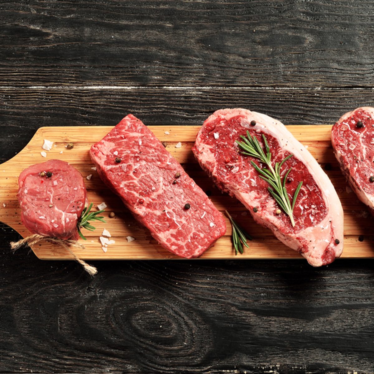Fresh raw Prime Black Angus beef steaks on wooden board: Tenderloin, Denver Cut, Striploin, Rib Eye