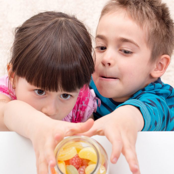 Children trying to take candy put aside