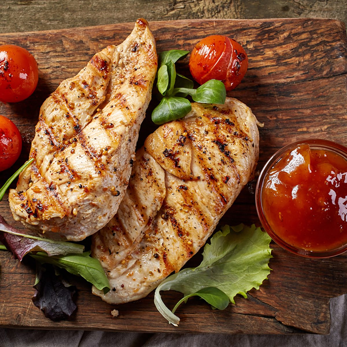 grilled chicken fillets on wooden cutting board