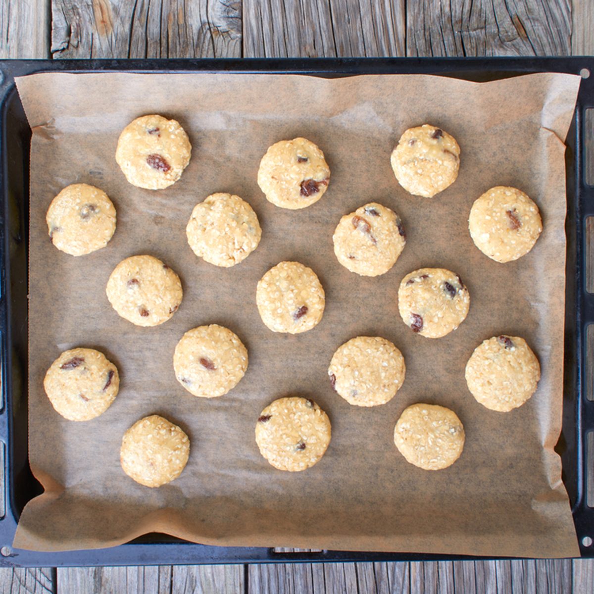 Uncooked oatmeal cookies on baking paper on a baking sheet