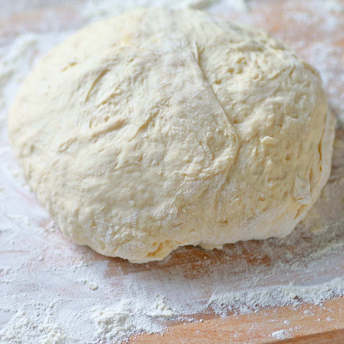 Bread dough kneaded and shaped into a ball for rising on a floured cutting board