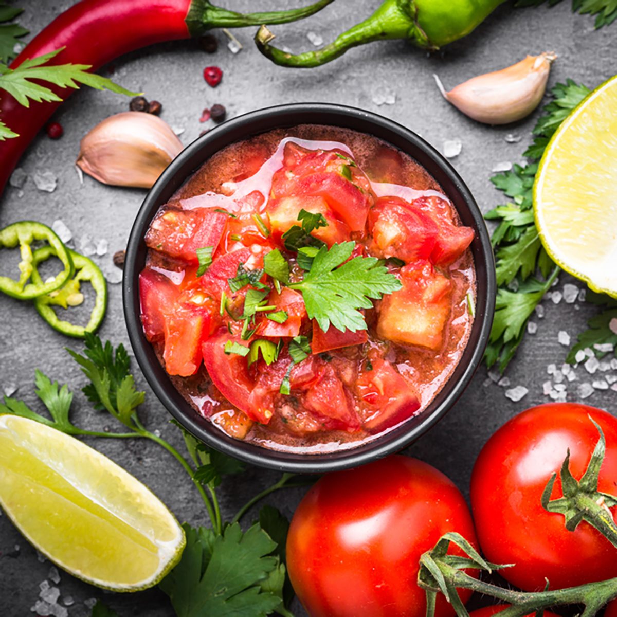 Traditional Latin American mexican salsa sauce and ingredients on black stone table.