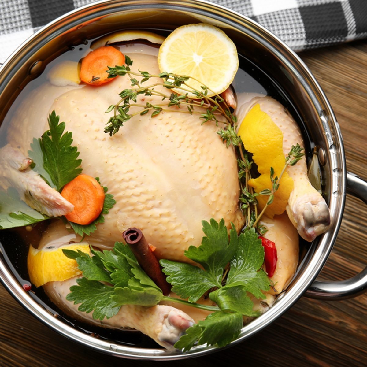 Cooking pot with turkey soaked in flavored brine on wooden table