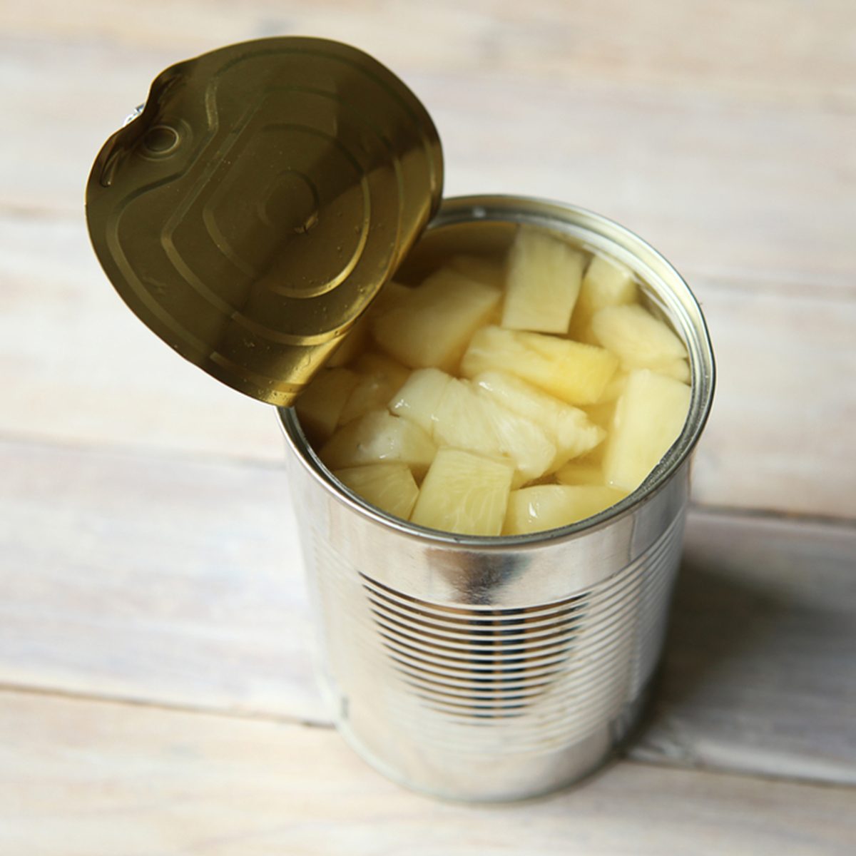 Opened tin can of canned pineapple pieces.
