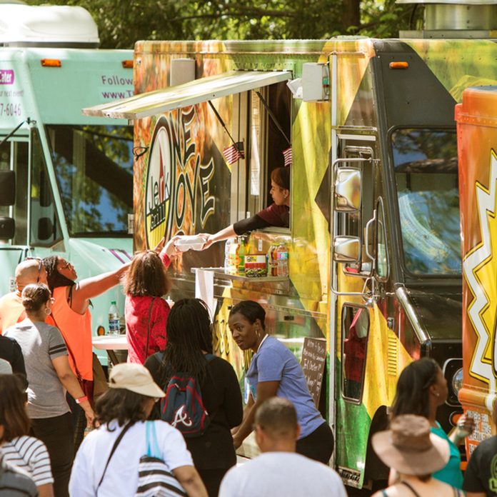 A crowd of people buy meals from food trucks lined up in Grant Park at the Food-o-rama festival