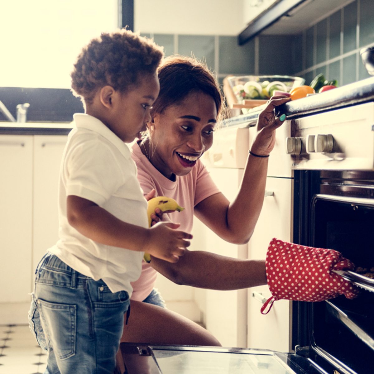 Black kid helping mom baking cookies in the kitchen