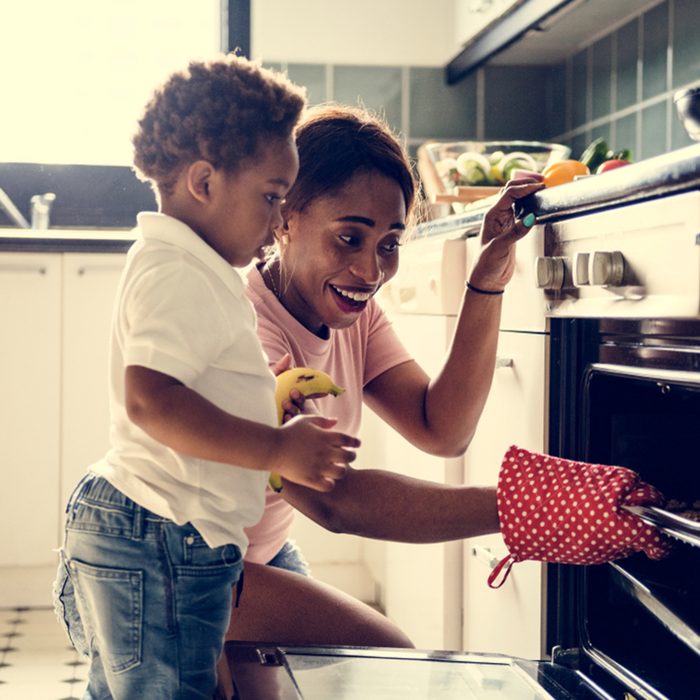 Black kid helping mom baking cookies in the kitchen