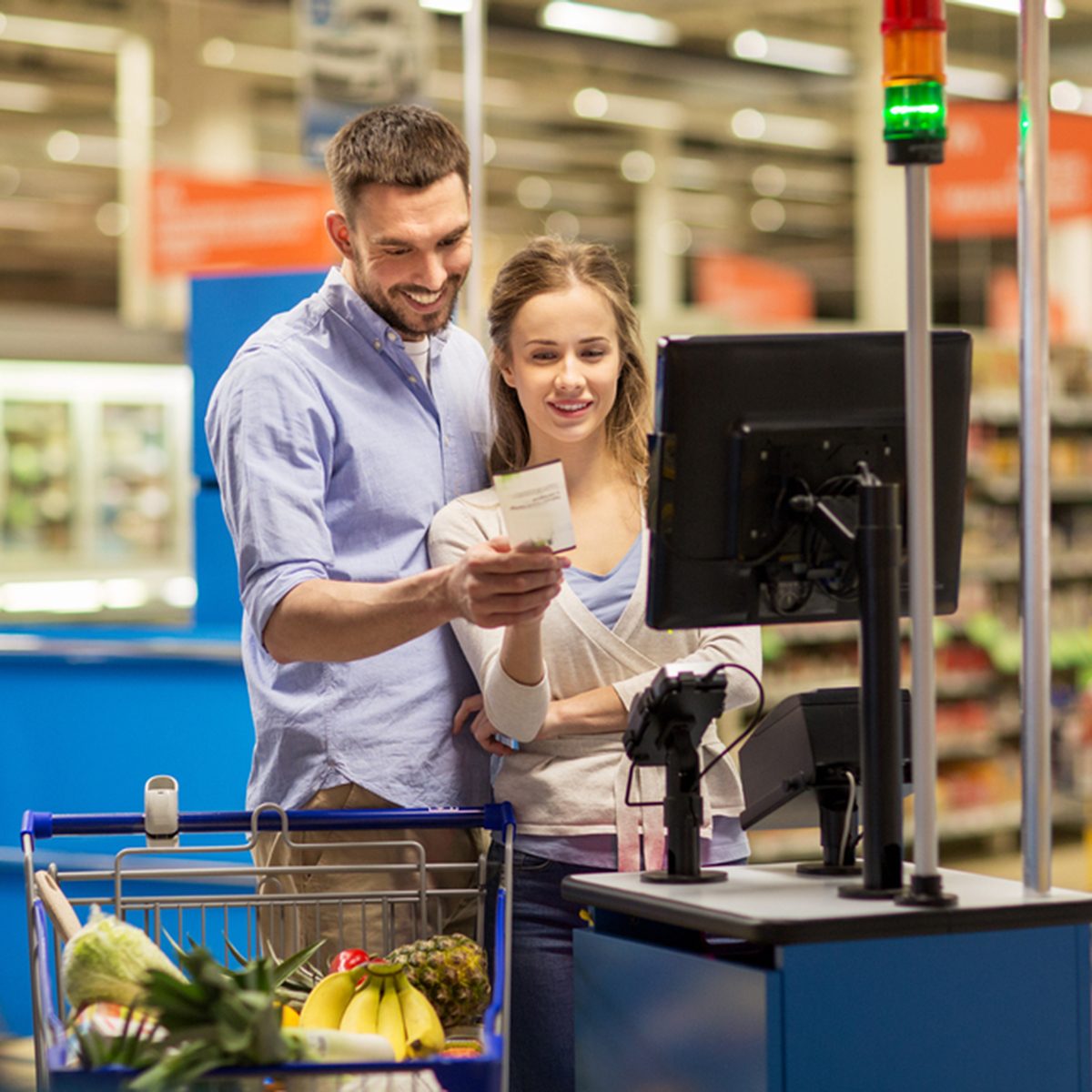 happy couple buying food at grocery store or supermarket self-service cash register