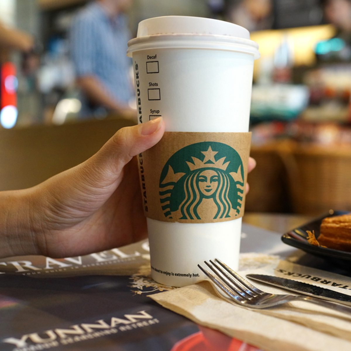 Close up female hand holding a cup of hot Starbucks coffee.