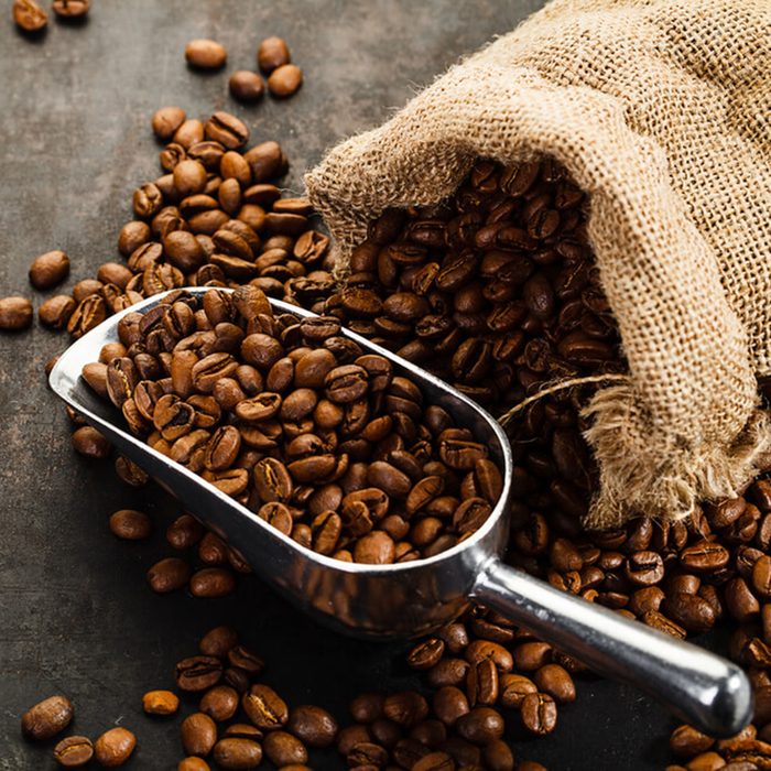 Cup of coffee, bag and scoop on old rusty background