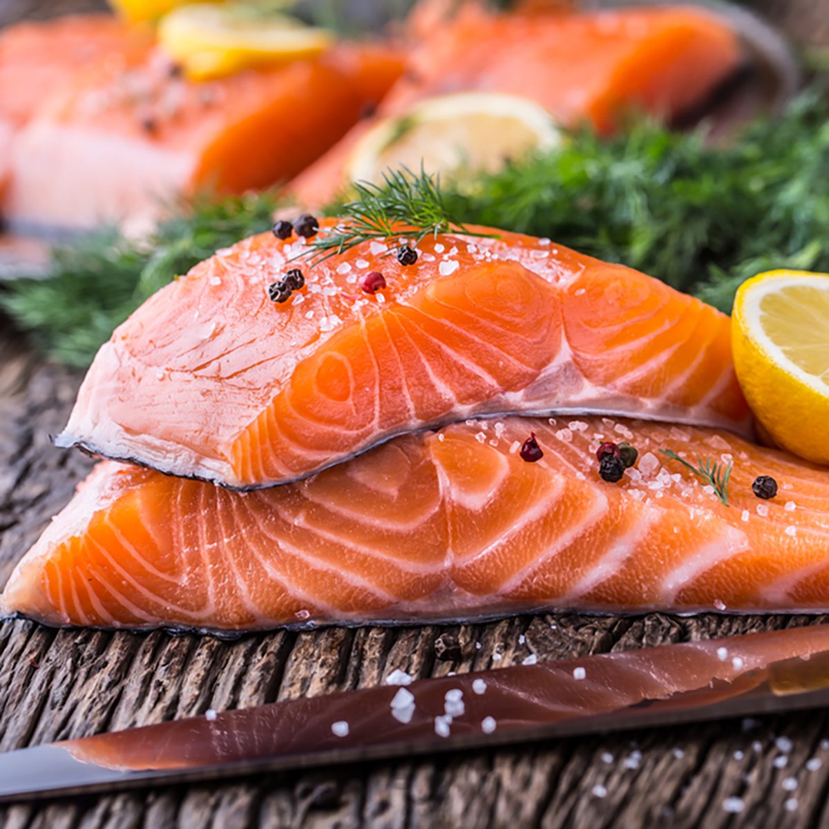 Raw salmon fillets pepper salt dill lemon and rosemary on wooden table
