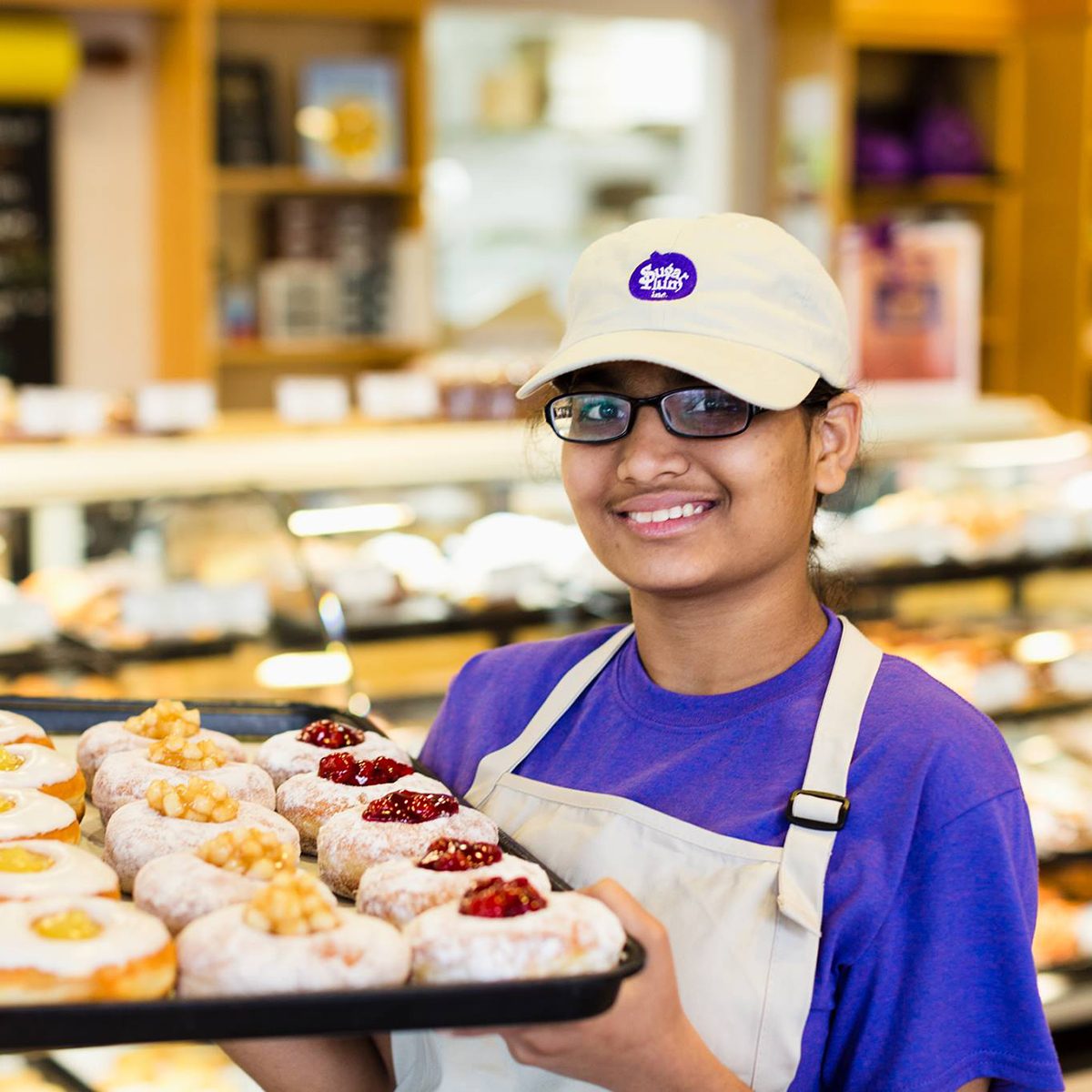 Baker holding tray of treats at Sugar Plum Bakery