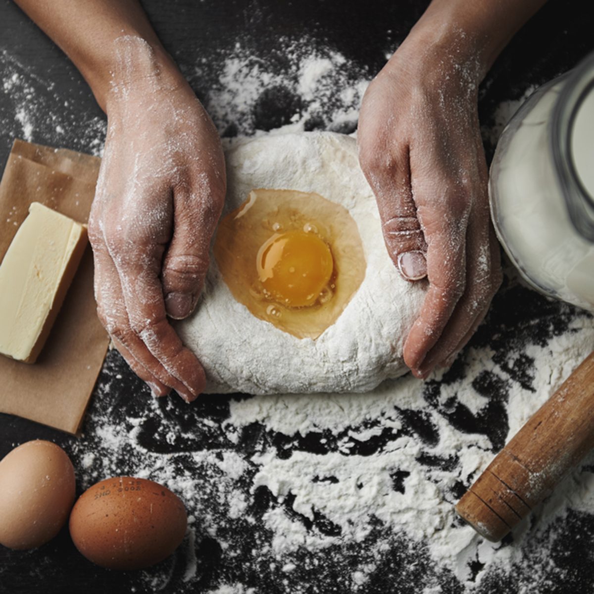 Professional female baker cooking dough with eggs, butter and milk for Christmas cookies.