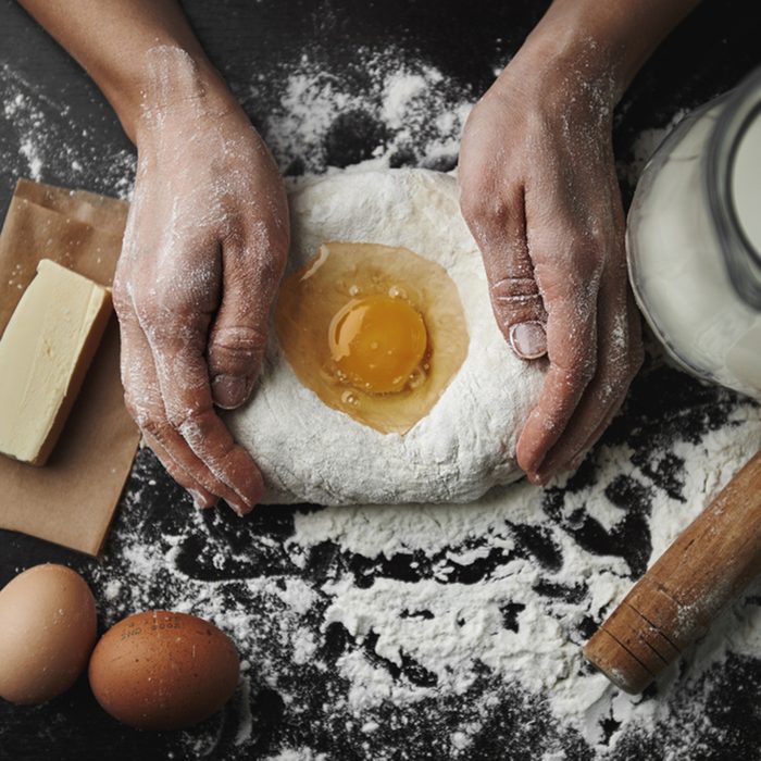 Professional female baker cooking dough with eggs, butter and milk for Christmas cookies.