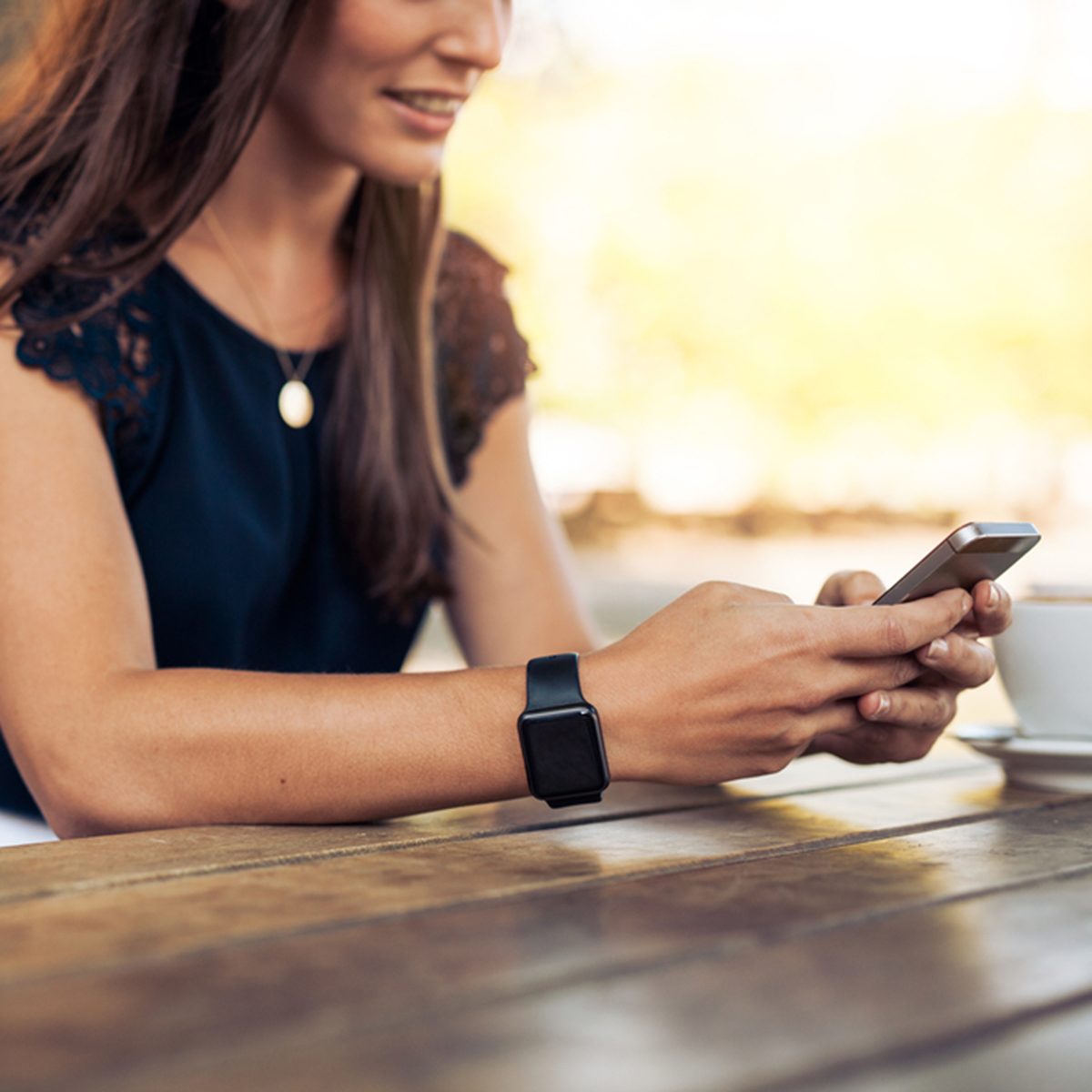 Woman typing text message on smart phone in a cafe.
