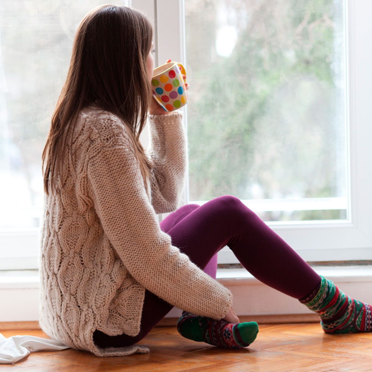Woman drinking in front of a window