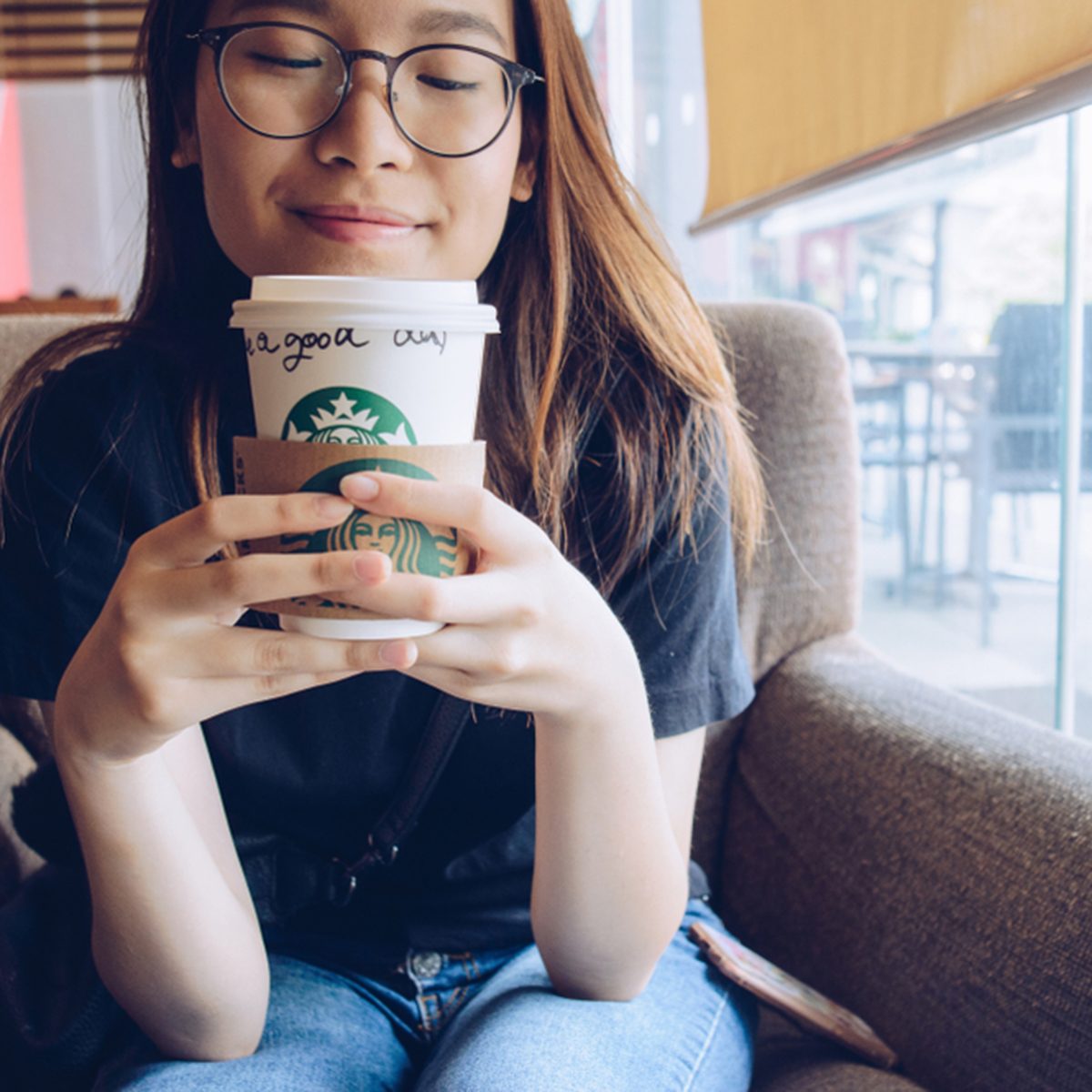 Chiang Rai, Thailand : May-23-2018 : Happy Asian girl holding a paper cup of Starbucks coffee in Starbucks coffee store.; Shutterstock ID 1101144779; Job (TFH, TOH, RD, BNB, CWM, CM): TOH