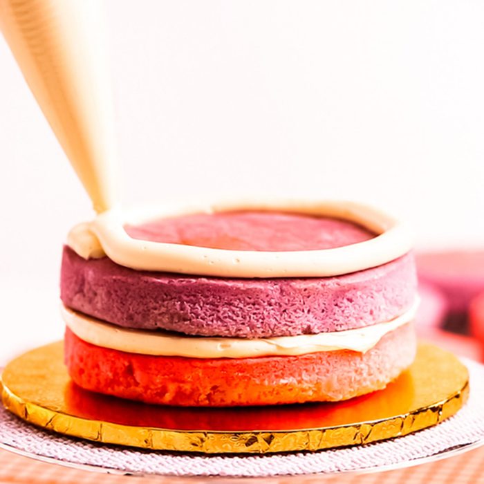 Baker assembling pink and purple cake layer to make unicorn cake for little girl