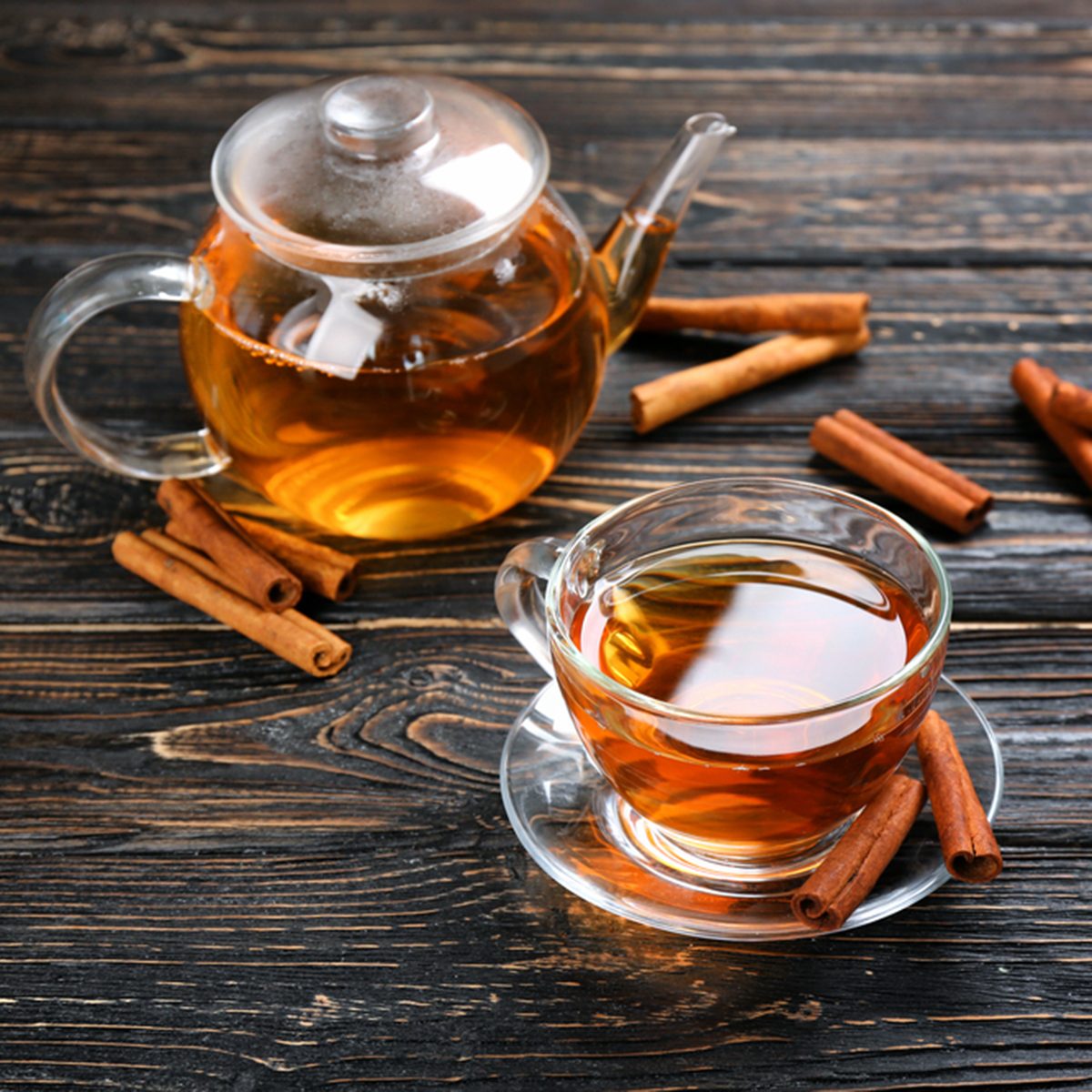 Cup and teapot with aromatic hot cinnamon tea on wooden table