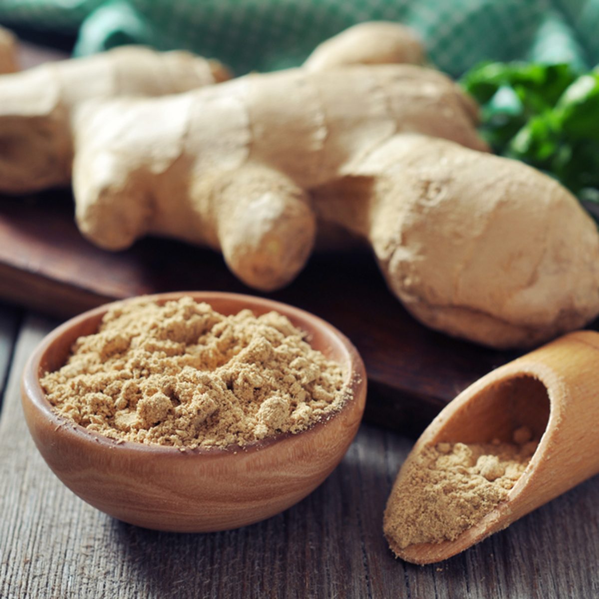 Fresh ginger root and ground ginger spice on wooden background