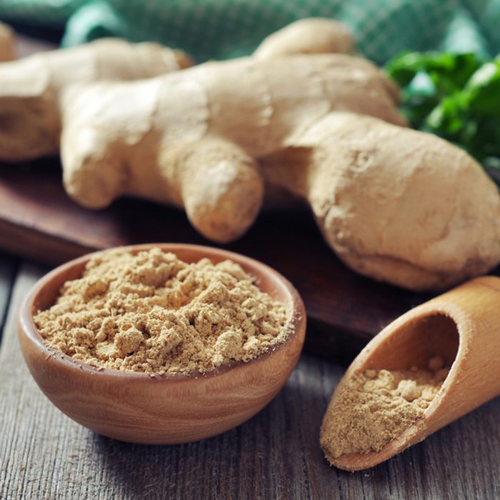 Fresh ginger root and ground ginger spice on wooden background