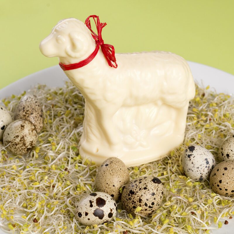 butter easter lamb on alfalfa sprouts with partridge eggs on white plate and green background