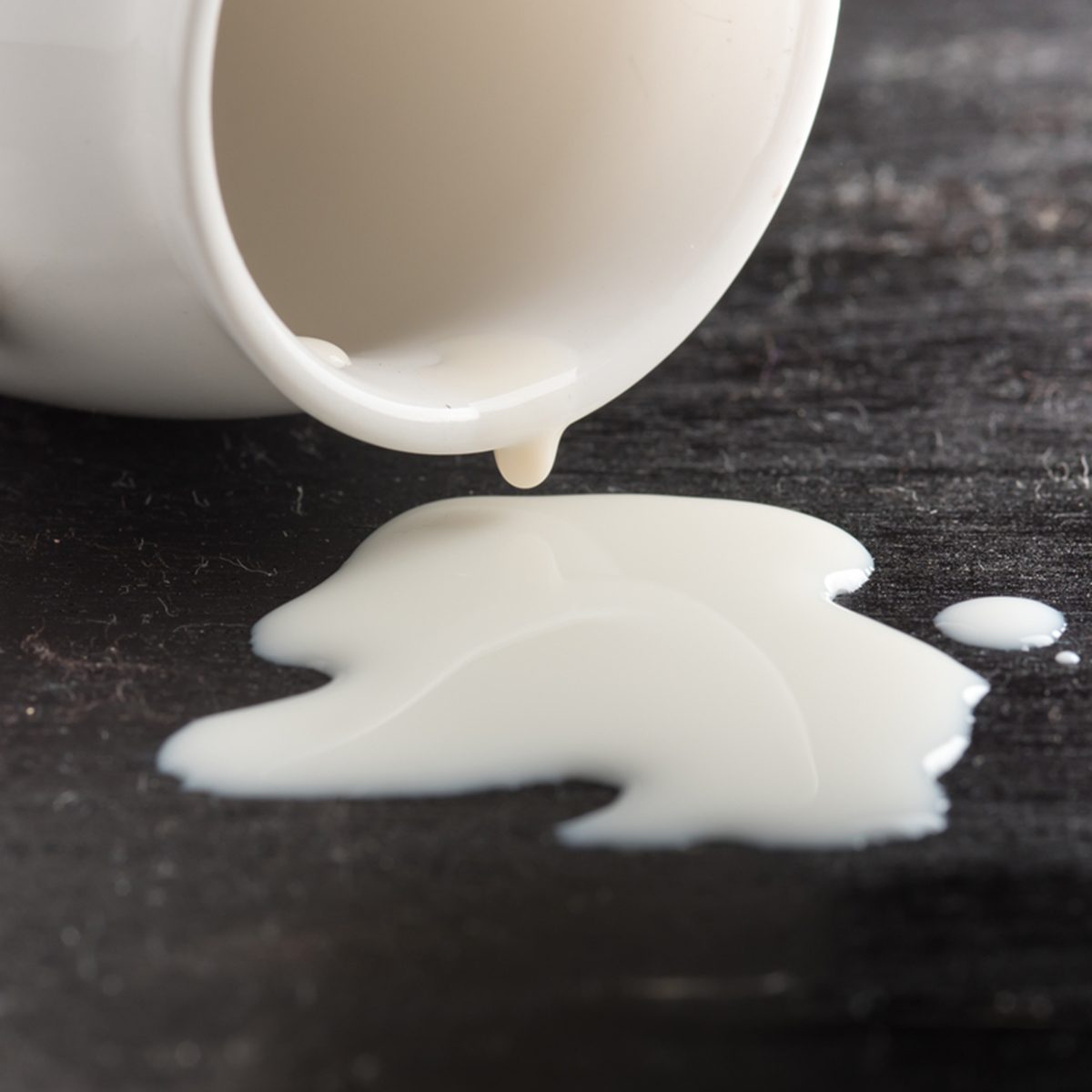 Milk spilled from glass on dark wooden
