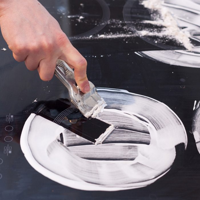 Housewife cleaning and polish electric cooker. Black shiny surface of kitchen top, hands with foam, glass scraper, bottle of cleaning agent; Shutterstock ID 675139813; Job (TFH, TOH, RD, BNB, CWM, CM): TOH