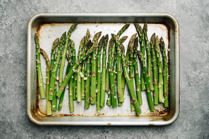 Oiled asparagus on a baking sheet ready to make roasted asparagus.