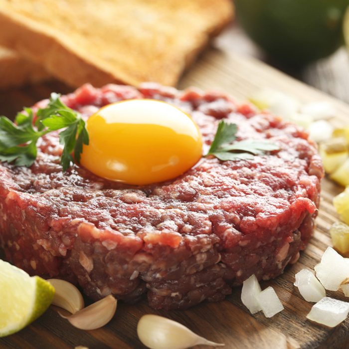 Beef tartare with egg yolk on a grey wooden table