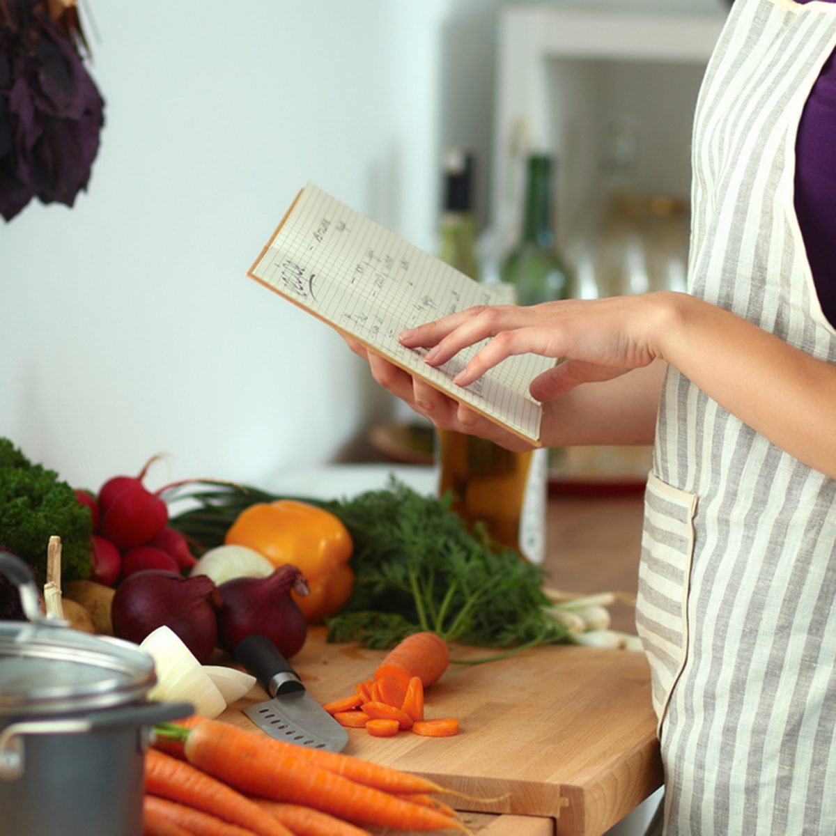 Young woman reading cookbook in the kitchen, looking for recipe