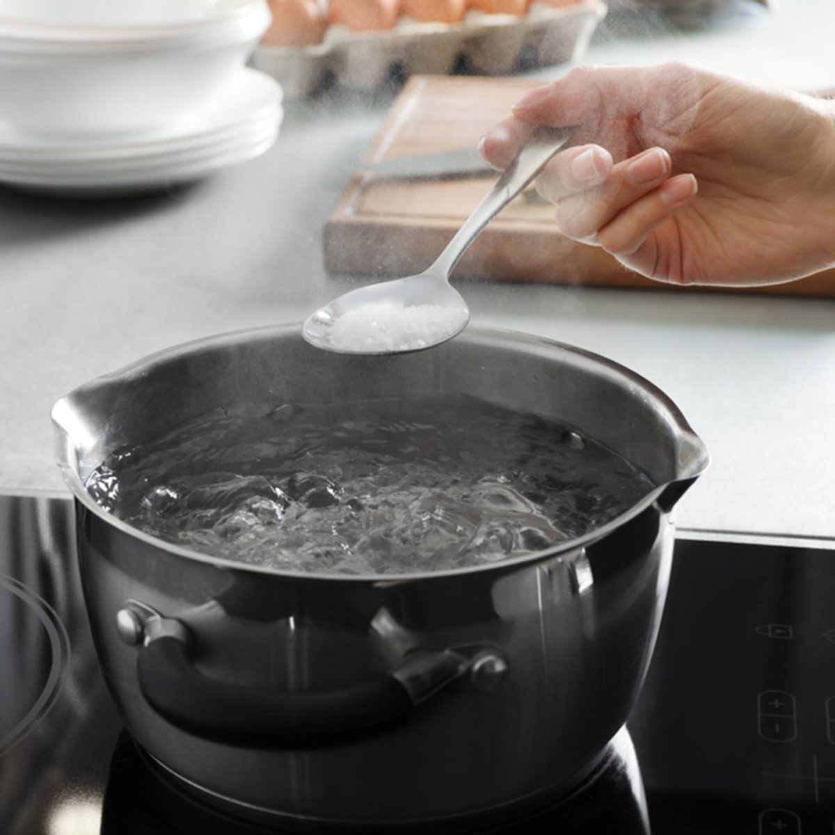 Woman salting boiling water in pot on stove, closeup; Shutterstock ID 1295704264
