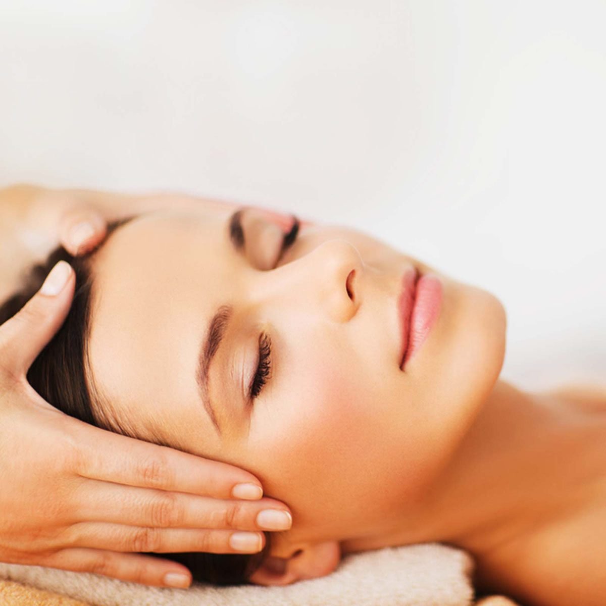 Woman with eyes closed getting her head massaged