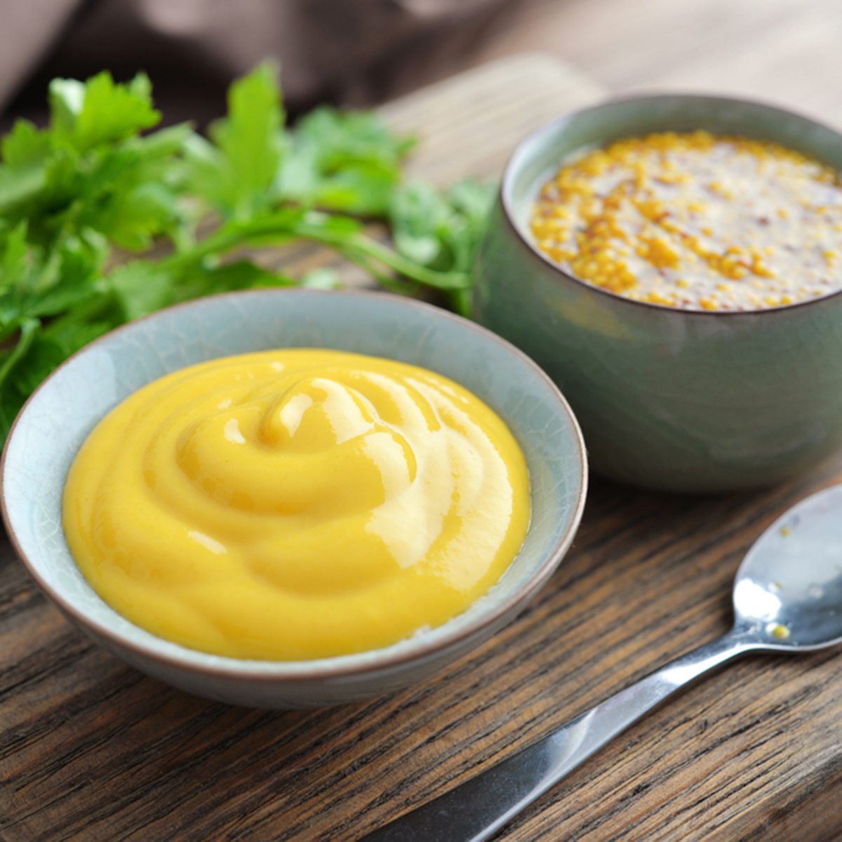 Mustard in the assortment: Dijon mustard and burning Russian mustard in bowls on wooden background