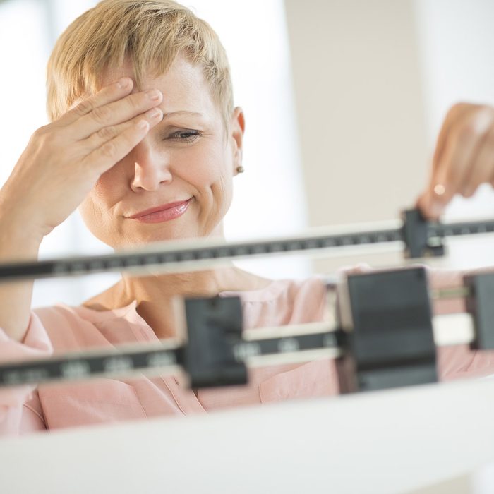 Doubtful woman adjusting weight scale; Shutterstock ID 159928418; Job (TFH, TOH, RD, BNB, CWM, CM): Taste of Home