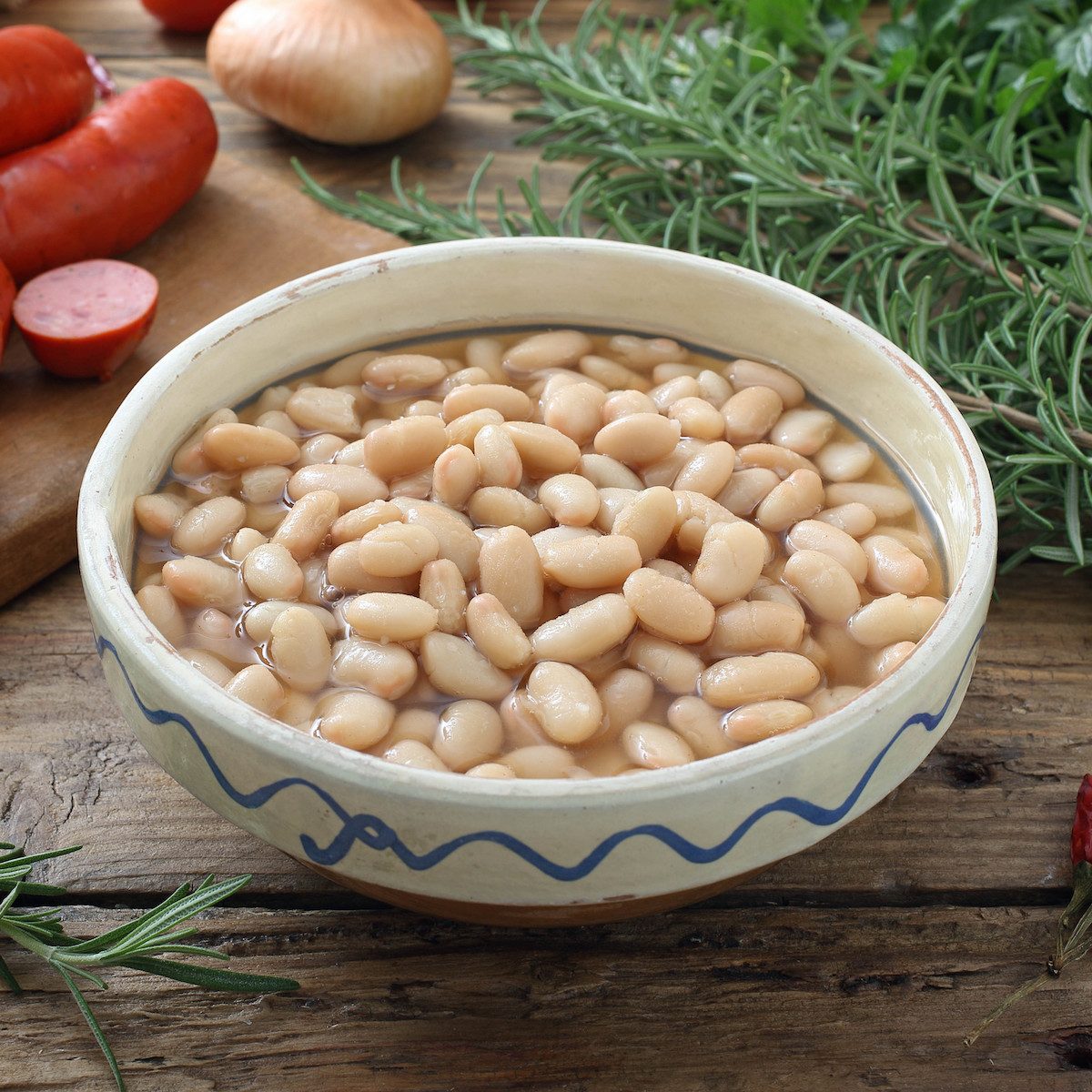 boiled white beans in ceramic bowl on a rustic chicken table background
