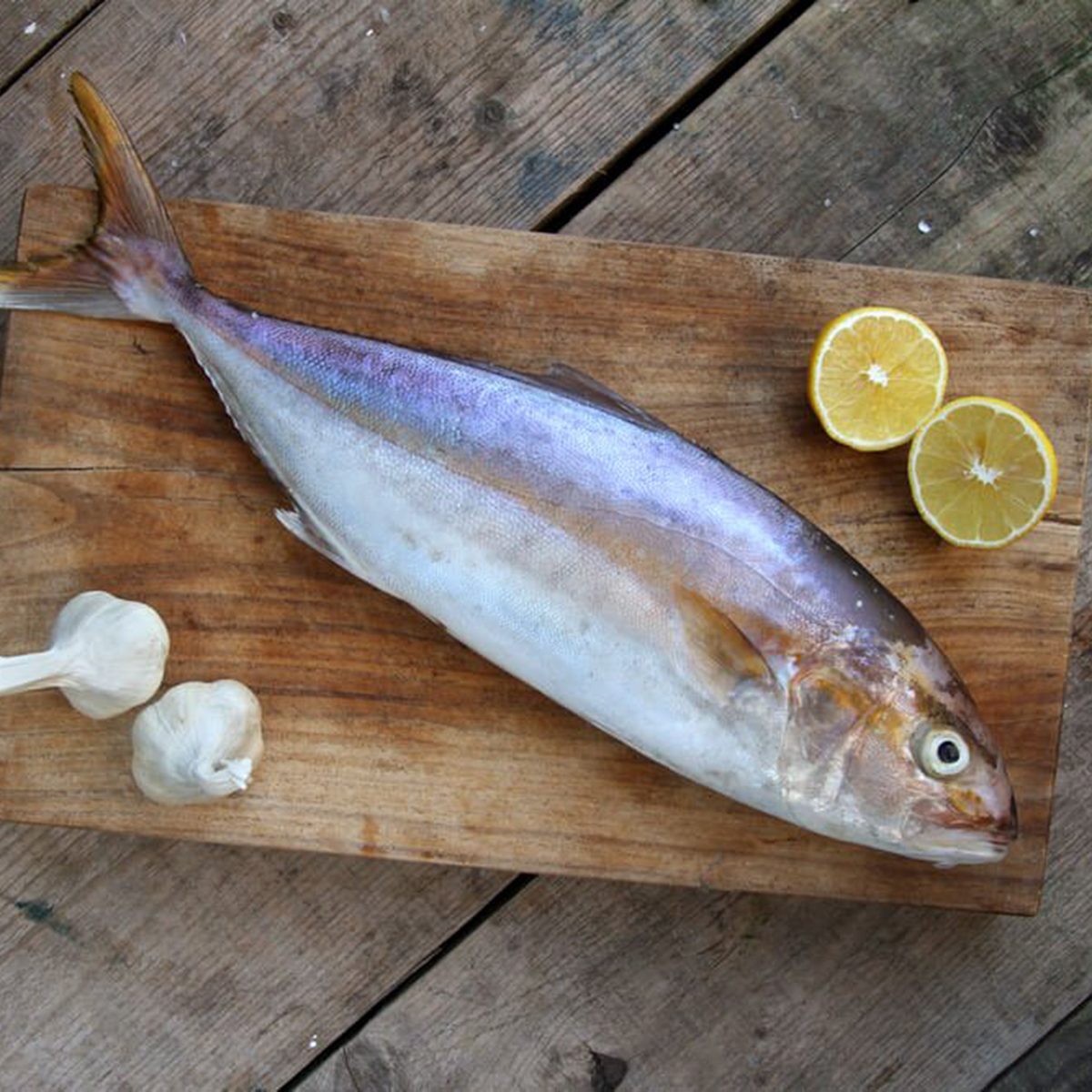 Whole fish beside garlic and lemons